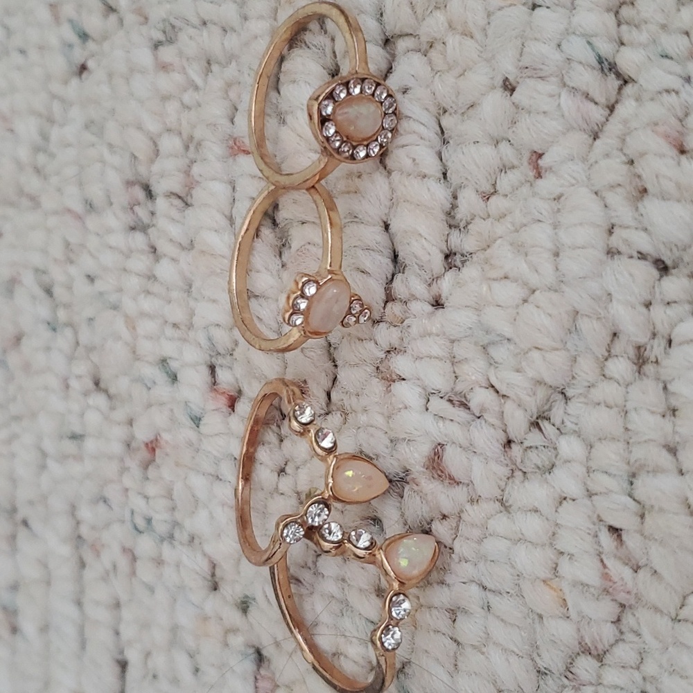 set of 4 gold rings with white and pink designs.